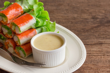 Fresh spring rolls with fresh vegetable and crab stick served with spicy salad cream dipping sauce. Rolls salad or fresh spring roll on white plate, healthy delicious food for appetizer or meal.