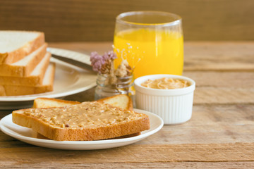 Toast bread with homemade peanut butter served with orange juice. Homemade toast bread with peanut butter on wood table for breakfast.Delicious toast bread with homemade peanut butter ready to served.