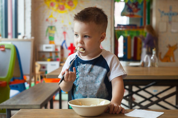 blonde toddler boy is eating in cafe