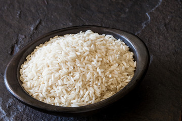 Raw rice grains in a traditional black clay dish