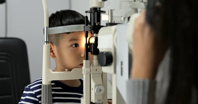 Young little boy undergo eye test at the optical store