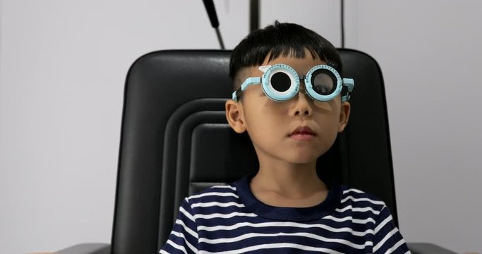 Young boy smiling while undergoing eye test with phoropter