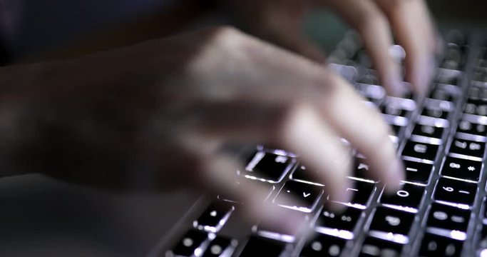 Typing on laptop computer at night