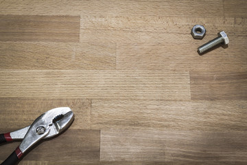 bolt nuts and plier on a wood background
