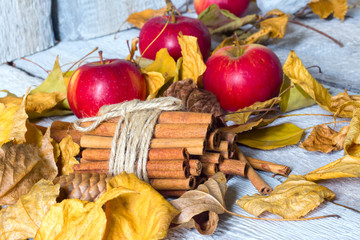 stylish rustic or autumn wallpaper with cinnamon and apple and leaves on wooden background. space for text. cozy mood. seasonal holidays concept