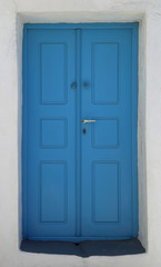 blue door of a home built into the volcanic rock hillside on the island of Santorini, Greece