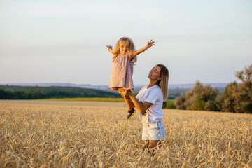 Naklejka na ściany i meble beautiful young mother and her daughter having fun at the wheat field