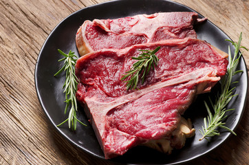 Raw fresh meat t-bone steak and seasoning on wooden background