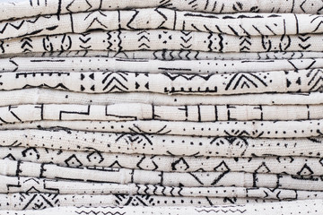 African textiles at a market stall featuring black and white patterns on hand-woven cloth by a...