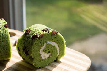 close up matcha green tea roll cake with evening light from the window
