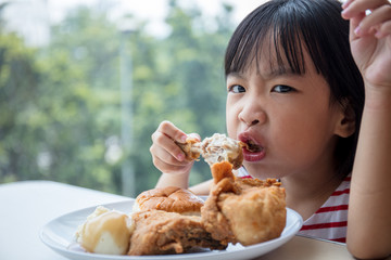 Asian Chinese little girl eating fried chicken
