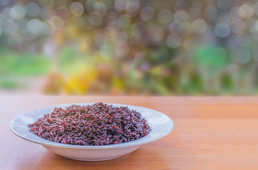 Abstract soft blurred and soft focus black sticky rice berry on the plate with the bokeh, beam light, lens flare effect tone background.Local food in Thailand.