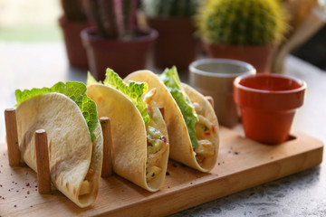Delicious tacos with fillet of fish and vegetables on wooden tray