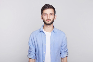 Portrait of Caucasian handsome brunette  guy with blue eyes, trendy hairdo and beard looking...