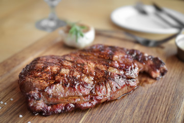 Delicious grilled steak on wooden board in restaurant