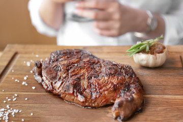 Delicious grilled steak on wooden board in restaurant