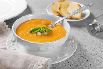 Bowl and spoon with delicious carrot soup on table