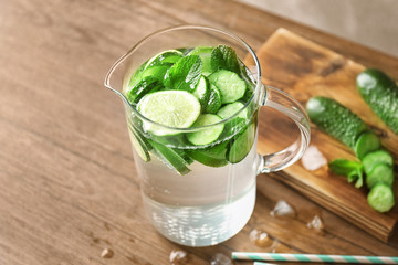 Delicious refreshing water with mint and cucumber in jar on wooden table