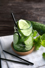 Delicious refreshing water with mint and cucumber in glass jar on table