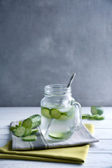 Delicious refreshing water with mint and cucumber in mason jar on table