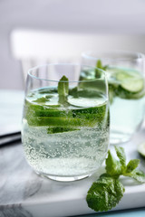 Delicious refreshing water with mint and cucumber in glass on table