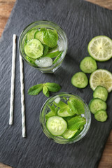 Delicious refreshing water with mint and cucumber in glasses on slate plate