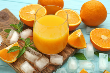 Composition with glass of fresh juice and oranges on color wooden background