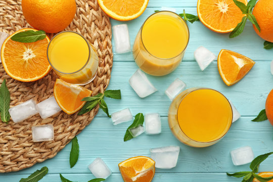 Composition with glasses of fresh juice and oranges on color wooden background
