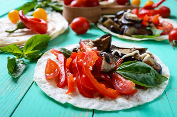 Vegetarian tacos with eggplant, cherry tomatoes, sweet peppers on a bright wooden background. Mexican snack.