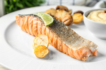 Plate with slice of delicious salmon and fish sauce on table