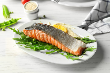 Plate with slice of delicious grilled salmon on table