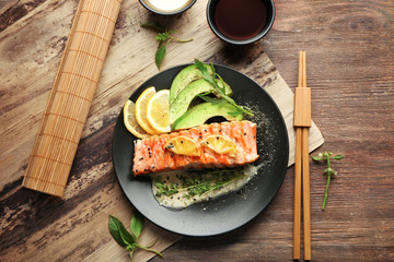 Plate with slice of delicious salmon and fish sauce on table