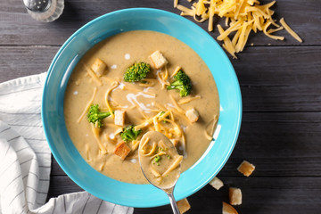 Spoon and plate with broccoli cheddar soup on table