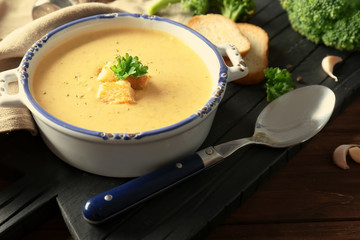 Broccoli cheddar soup in casserole on wooden board