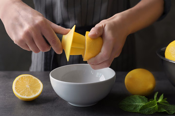 Man extracting lemon juice with plastic citrus reamer - obrazy, fototapety, plakaty