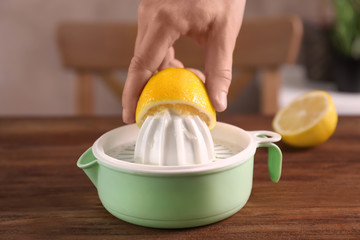 Man's hand pressing lemon to plastic squeezer