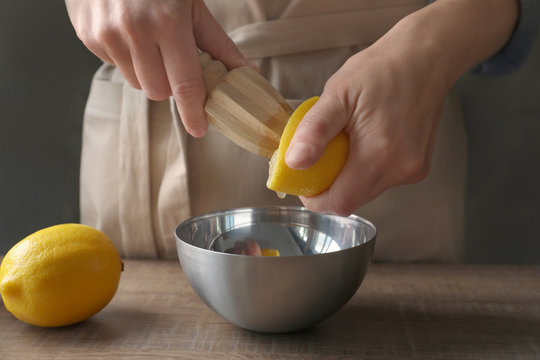 Man extracting lemon juice with wooden citrus reamer