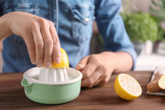 Woman extracting lemon juice with plastic squeezer
