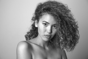 Portrait of a curly woman with freckles and naked shoulders.