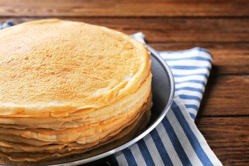 Stack of delicious thin pancakes on frying pan, closeup
