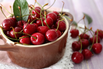 Ripe cherries in brown ceramic bowl on light background