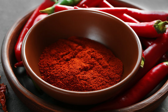 Red chili powder and raw pepper pods on table