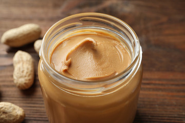 Jar with creamy peanut butter on table