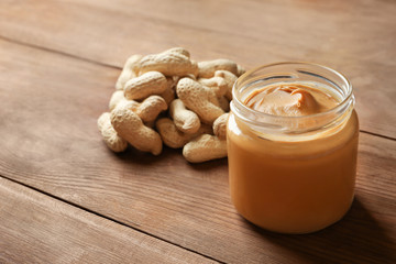 Jar with creamy peanut butter on table