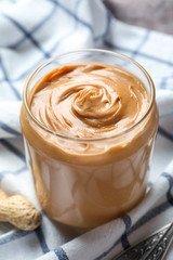 Jar with creamy peanut butter on napkin