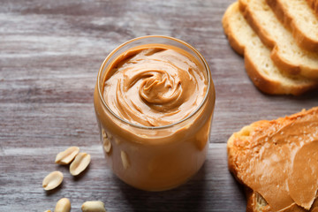 Jar with creamy peanut butter on table