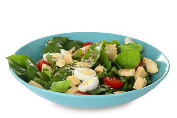 Salad with quail eggs and spinach in plate isolated on white