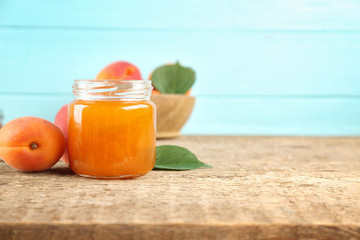 Apricot jam in jar with ripe juicy fruit on table
