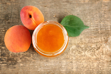 Apricot jam in jar with ripe juicy fruit on table