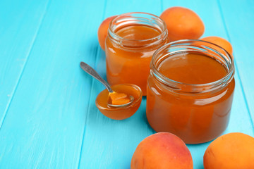 Apricot jam in jars and bowl with spoon on table